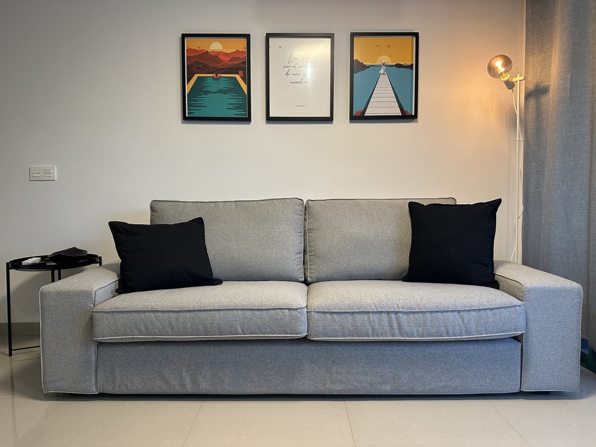 Apartment One's living room, with a sofa and framed prints on a light wall