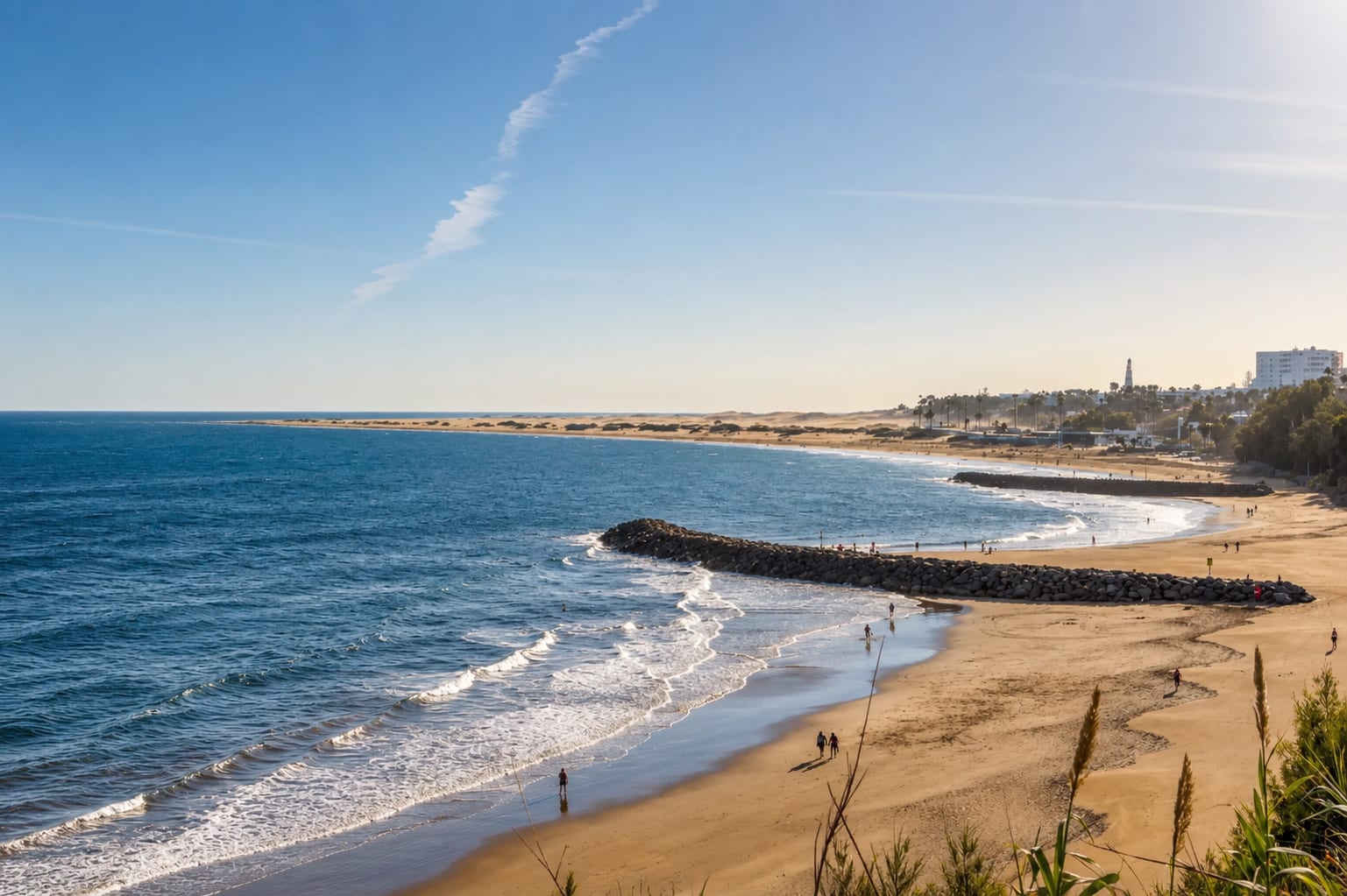 Sandy coastline with waves and stone breakwaters