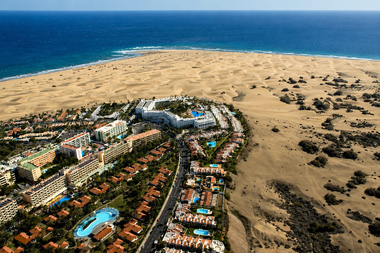 Aerial view of coastal buildings beside a dune landscape