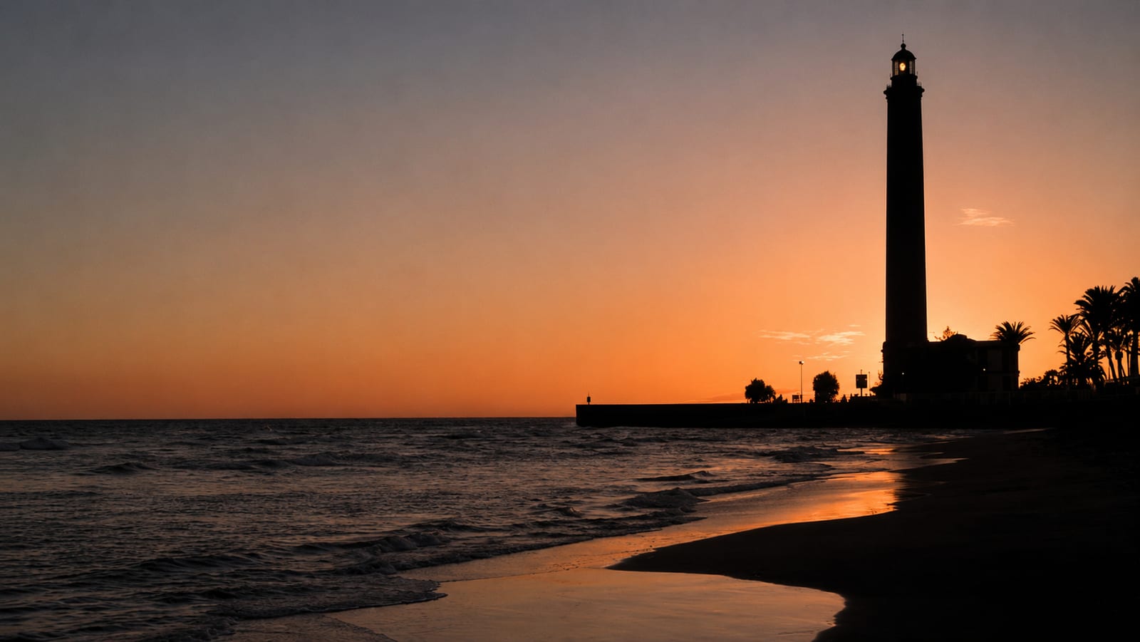 Lighthouse silhouette on the beach at sunset